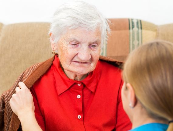 young caregiver wrap elderly woman with warm sweater