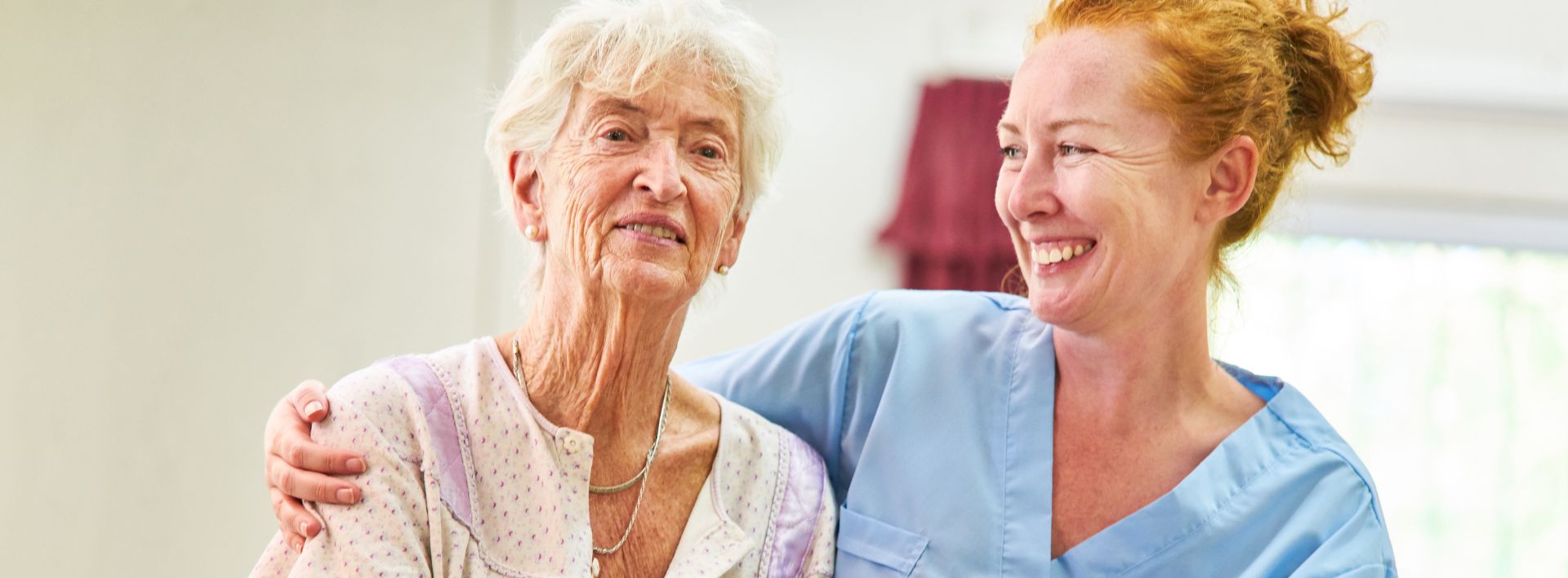 caring geriatric nurse hugging and comforting old woman